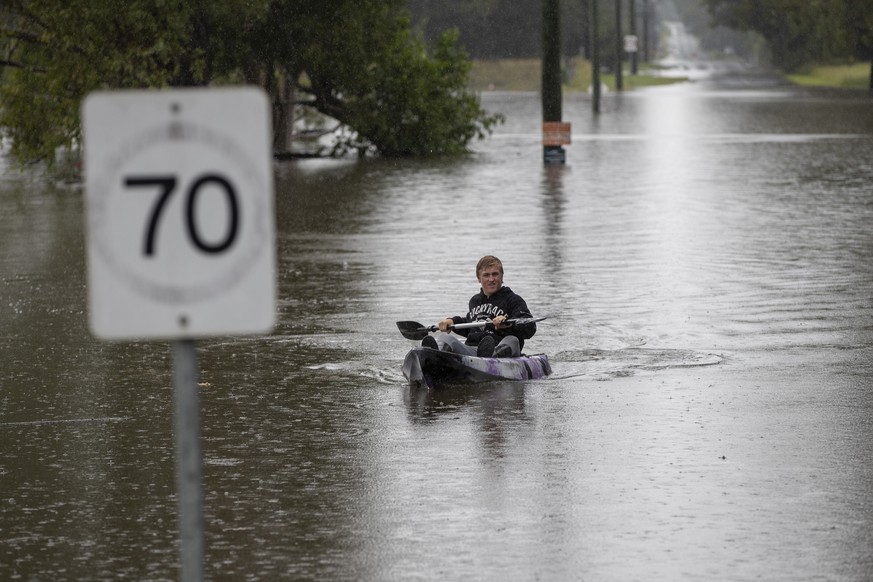 A man paddles through flood waters at Londonderry on the western outskirts of Sydney, Australia, Monday, March 22, 2021. Hundreds of people have been rescued from floodwaters that have isolated dozens ...