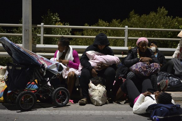 Refugees and migrants with their children gather on a bridge as fire burns at the Moria refugee camp on the northeastern Aegean island of Lesbos, Greece, on Wednesday, Sept. 9, 2020. Fire Service offi ...