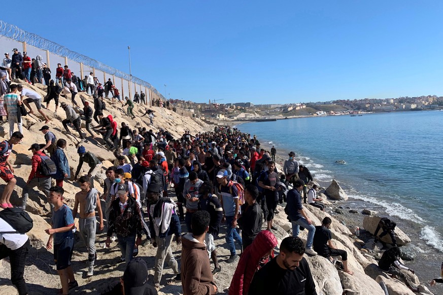 epa09211144 Dozens of people try to cross the border fence separating Fnideq (Castillejos, Morocco) and the Spanish city of Ceuta, located in northern Africa, 19 May 2021, following the arrival of up  ...