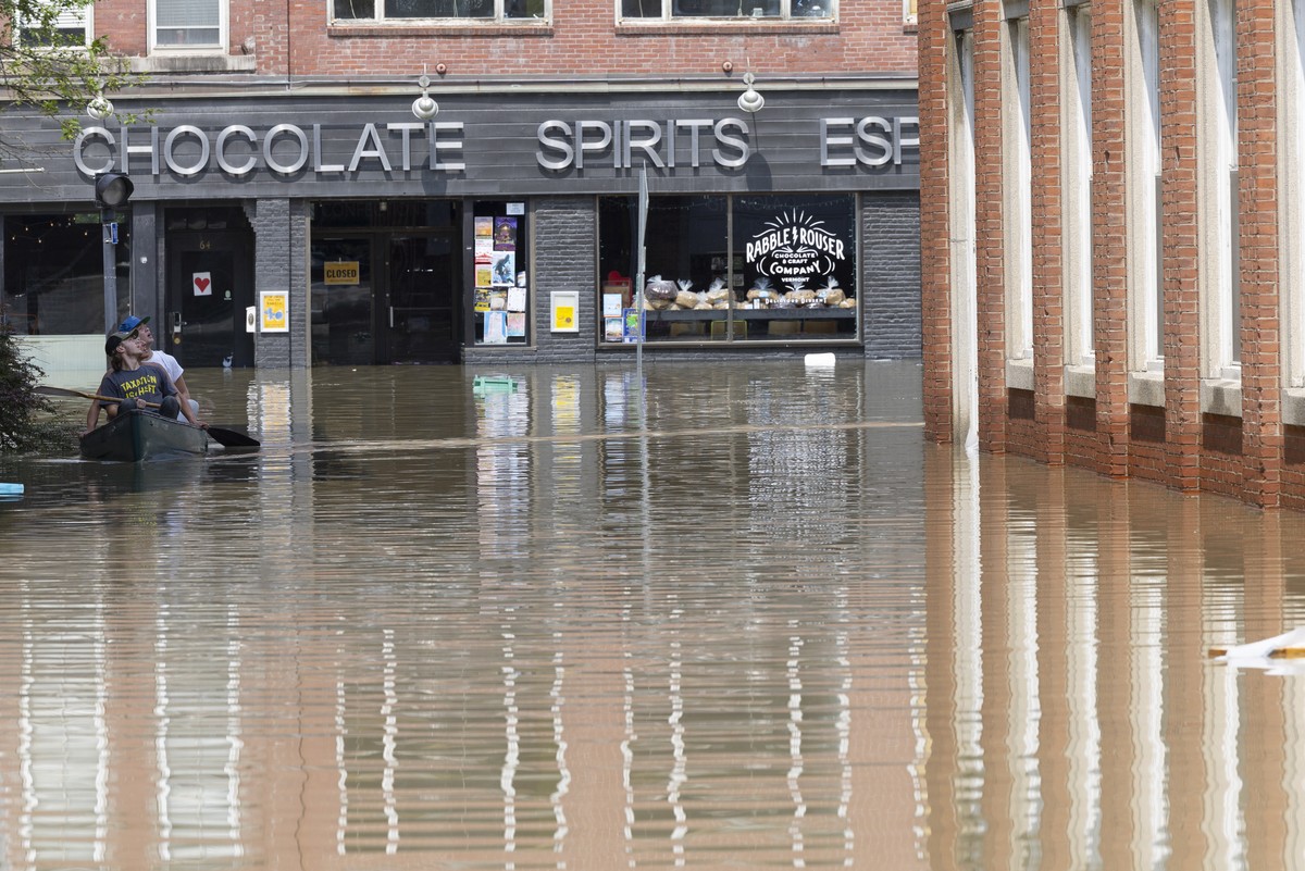epa10740211 People in a canoe survey the flooding as they navigate the streets in Montpelier, Vermont, USA, 11 July 2023. Heavy rain, up to eight inches (20.3 cm) prompted flooding of the Winooski Riv ...