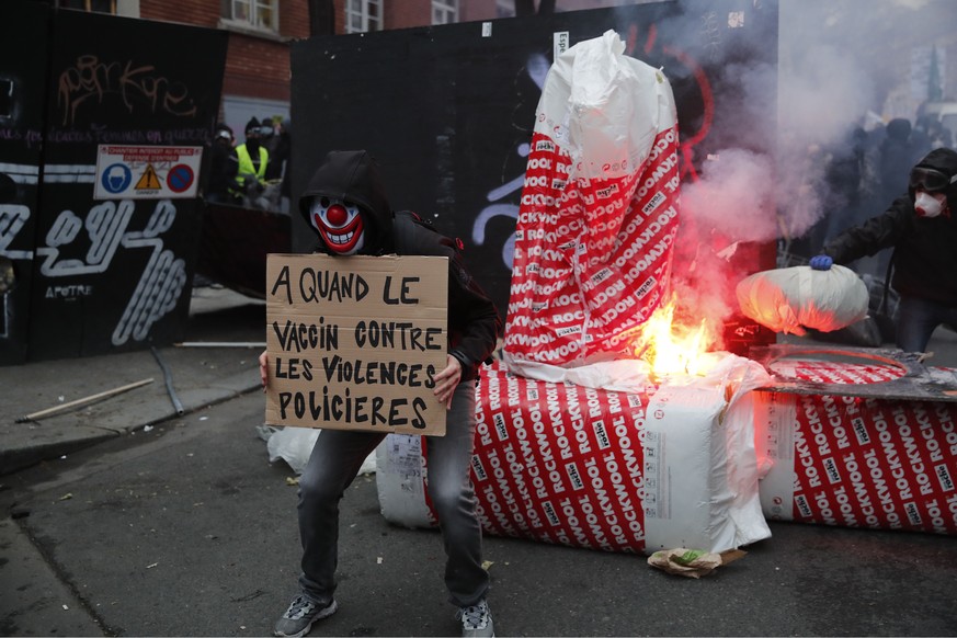 A protester holds a poster reading &quot; When a vaccine against police violence&quot; in front a barricade during a demonstration Saturday, Dec. 5, 2020 in Paris. Thousands marched in protests around ...