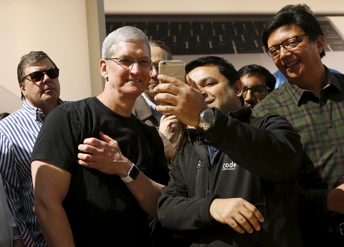 Apple CEO Tim Cook displays his Apple Watch while having a photograph taken by a customer in Palo Alto, California April 10, 2015. Customers flocked to Apple Inc's stores around the world on Frid ...