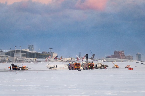 epa11903781 Emergency crews gather at the accident site where a Delta Air Lines flight flipped upside down while landing at Toronto Pearson International Airport in Mississauga, Canada, 17 February 20 ...