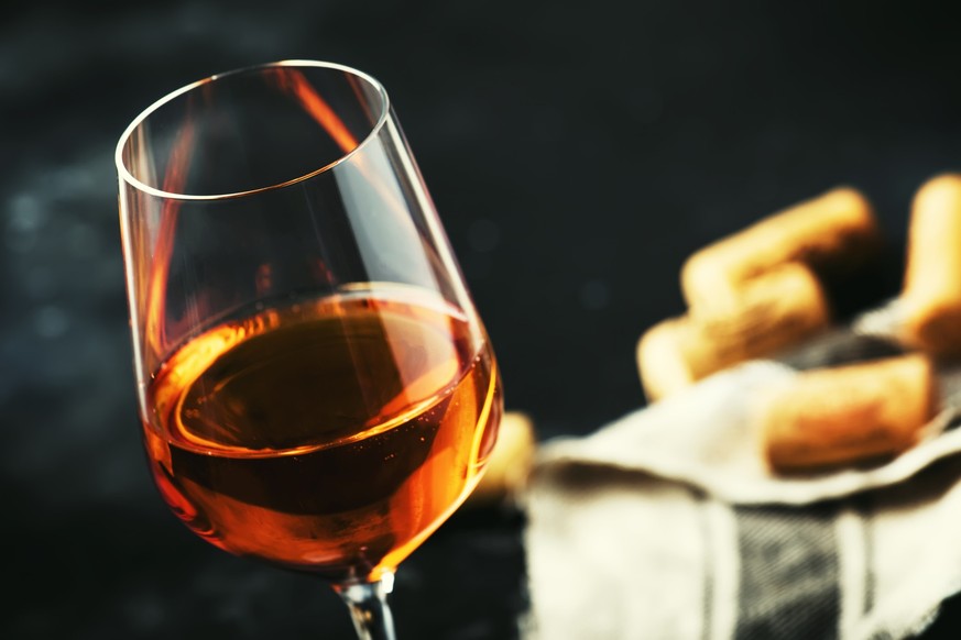 Trendy food and drink, orange wine in glass, gray table, space for text, selective focus