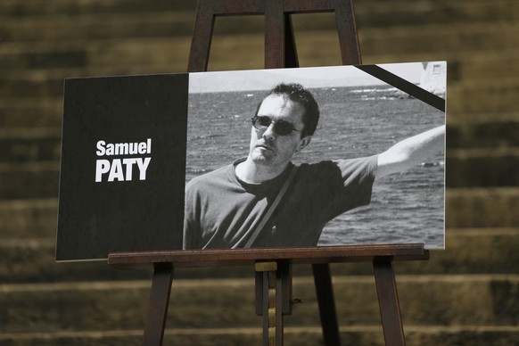 The portrait of slain teacher Samuel Paty with a black ribbon is displayed Tuesday, Oct.20, 2020 on the steps of the National Assembly in Paris. A memorial march will be held Tuesday evening near Pari ...