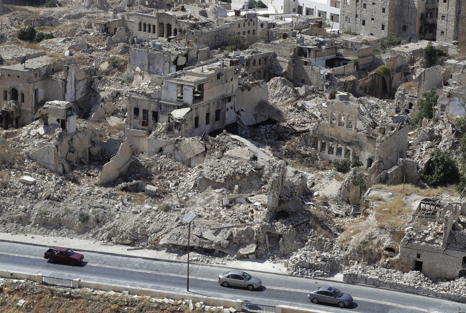 FILE - People drive their cars past destroyed buildings in the city of Aleppo, Syria, Aug. 16, 2018. The Russian airstrike on a children���s and maternity hospital in the Ukrainian port city of Mariup ...