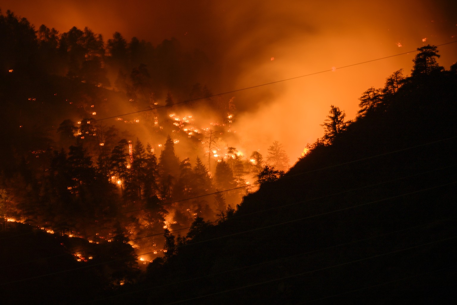 De la fumee et des flammes s'echappent de la foret en feu au dessus des communes de Bitsch et Ried-Moerel ce lundi 17 juillet 2023 a Bitsch. Un incendie de foret s'est declare lundi au-dessu ...