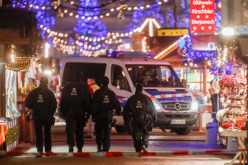 epa06362157 Policemen walk on an empty Christmas market after it was evacuated by police, in Potsdam, Germany, 01 December 2017. Police said they had found an explosive device at Potsdam Christmas mar ...