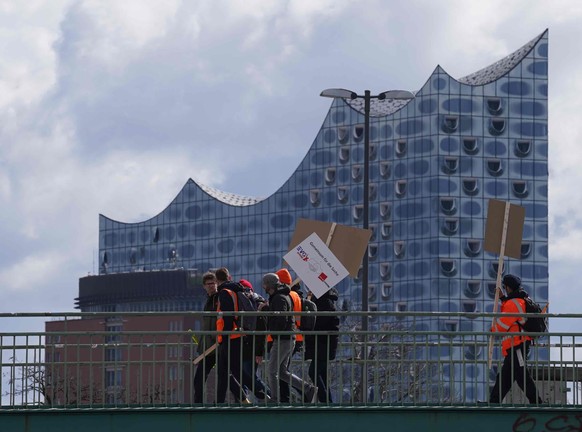 27.03.2023, Hamburg: Teilnehmer am Warnstreik gehen mit Plakaten und Fahnen nach einer Kundgebung zu einer U-Bahn-Station. Mit einem gro�angelegten bundesweiten Warnstreik haben die Gewerkschaften EVG ...