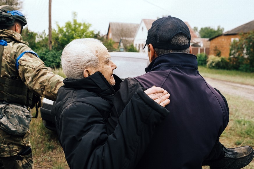 epa11336718 Local man Valentyn, 60, carries in his arms his disabled father, Viktor, 84, as they evacuate from territories bordering Russia, in the city of Vovchansk, Kharkiv region, northeastern Ukra ...