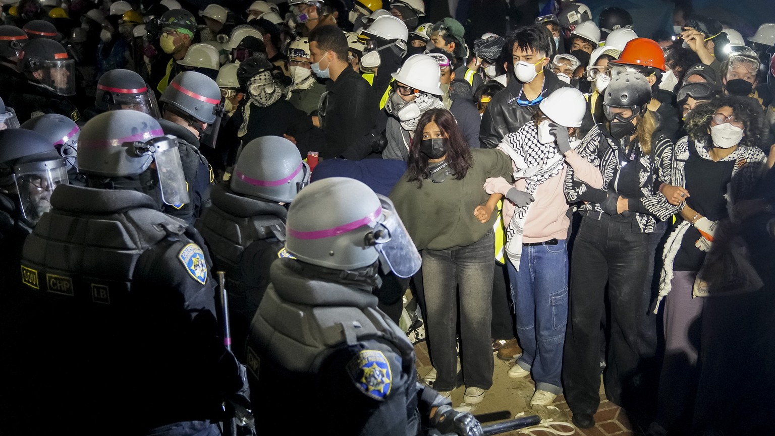 epa11314342 Police officers confront demonstrators gathered at the ongoing encampment of pro-Palestinian protesters on the campus of University of California Los Angeles (UCLA) in Los Angeles, Califor ...