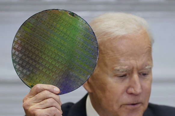 President Joe Biden holds up a silicon wafer as he participates virtually in the CEO Summit on Semiconductor and Supply Chain Resilience in the Roosevelt Room of the White House, Monday, April 12, 202 ...