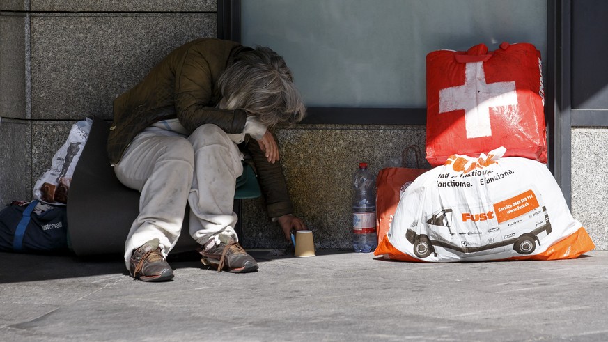 A homeless woman sitting on her luggage next to her bag with the Swiss cross, in Geneva, Switzerland, Saturday, August 13, 2016. (KEYSTONE/Salvatore Di Nolfi)