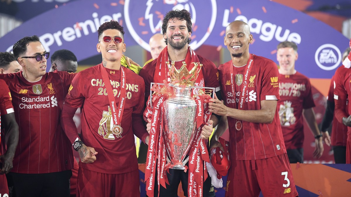 Liverpool's Fabinho, right, Liverpool's goalkeeper Alisson, center, and Roberto Firmino, all from Brazil, celebrate with the English Premier League trophy following the English Premier Leagu ...