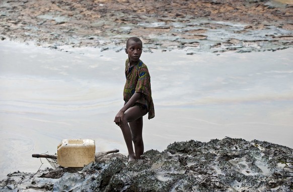 epa08972631 (FILE) - A boy with a fishnet standing on the oil stained bank of a creek near Goi, Ogoniland, Nigeria (reissued 29 January 2021). An appeals court in The Hague on 29 January 2021 ruled th ...