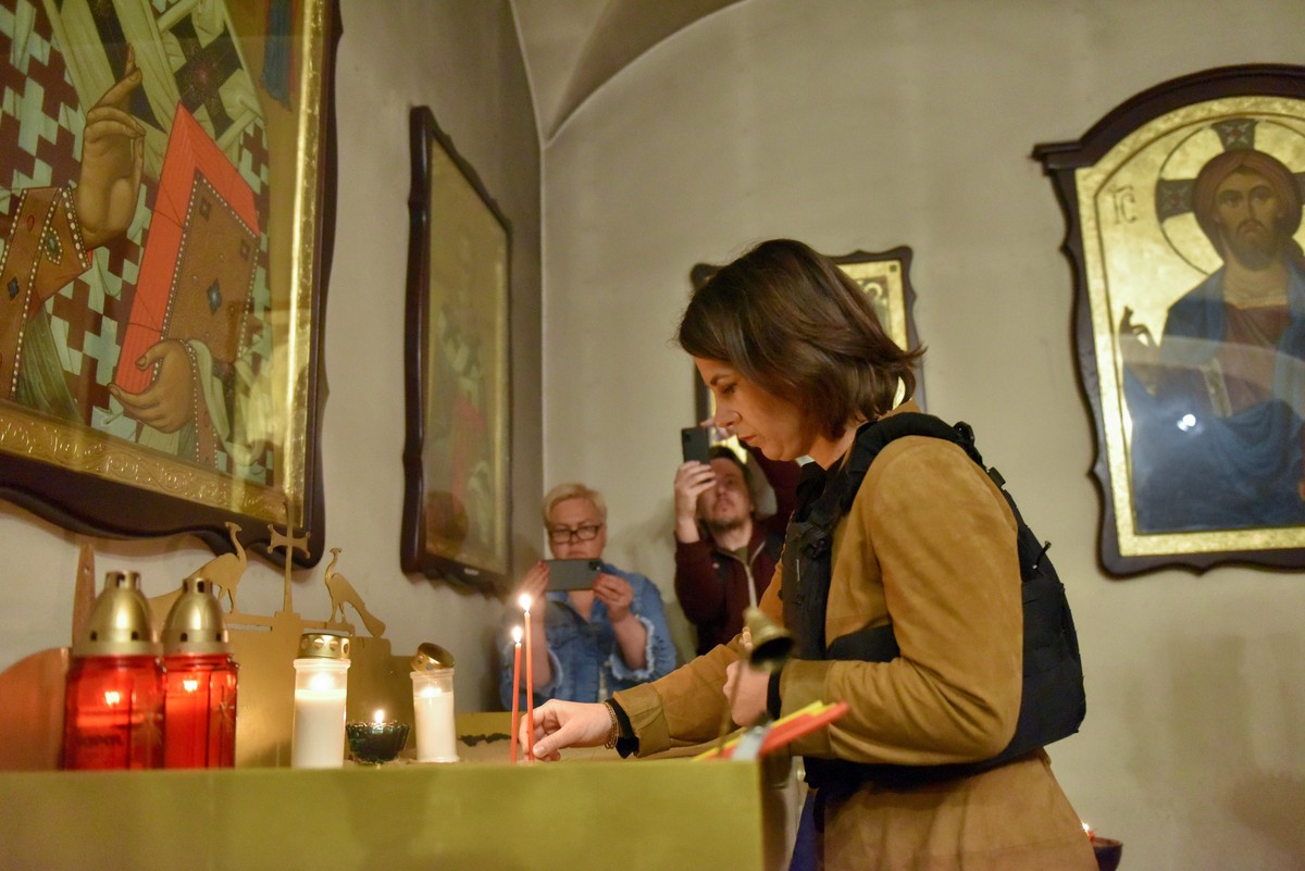 epa09937854 German Foreign Minister Annalena Baerbock lights a candle at the Church of St. Andrew Pervozvannoho All Saints during her visit to the church and adjacent mass grave sites in Bucha, Ukrain ...