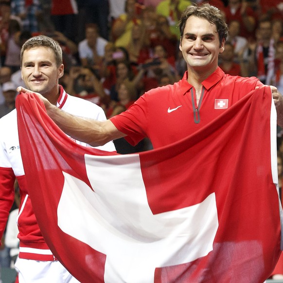 Roger Federer, right, of Switzerland, celebrates next to his teammate Marco Chiudinelli, left, with a Swiss flag after beating the Italy, at the Davis Cup World Group Semifinal match between Switzerla ...