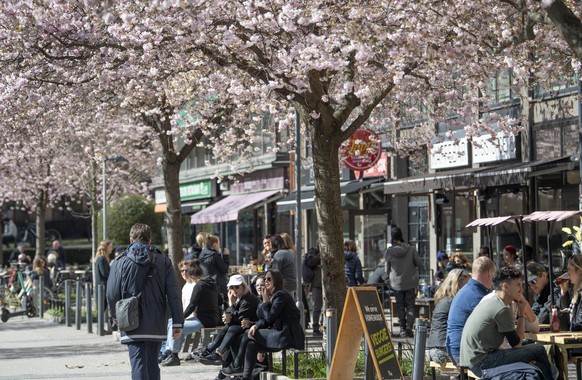 People sit outside in the sun in central Stockholm Saturday April 11, 2020. Swedish authorities have advised the public to practice social distancing because of the coronavirus pandemic, but still all ...