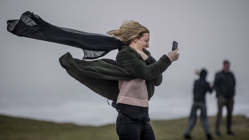 epa10473505 A person using a mobile phone stands against the wind as storm Otto hitsBovbjerg Lighthouse in West Jutland, Denmark, 17 February 2023. The Danish Meteorological Institute (DMI) warned on  ...