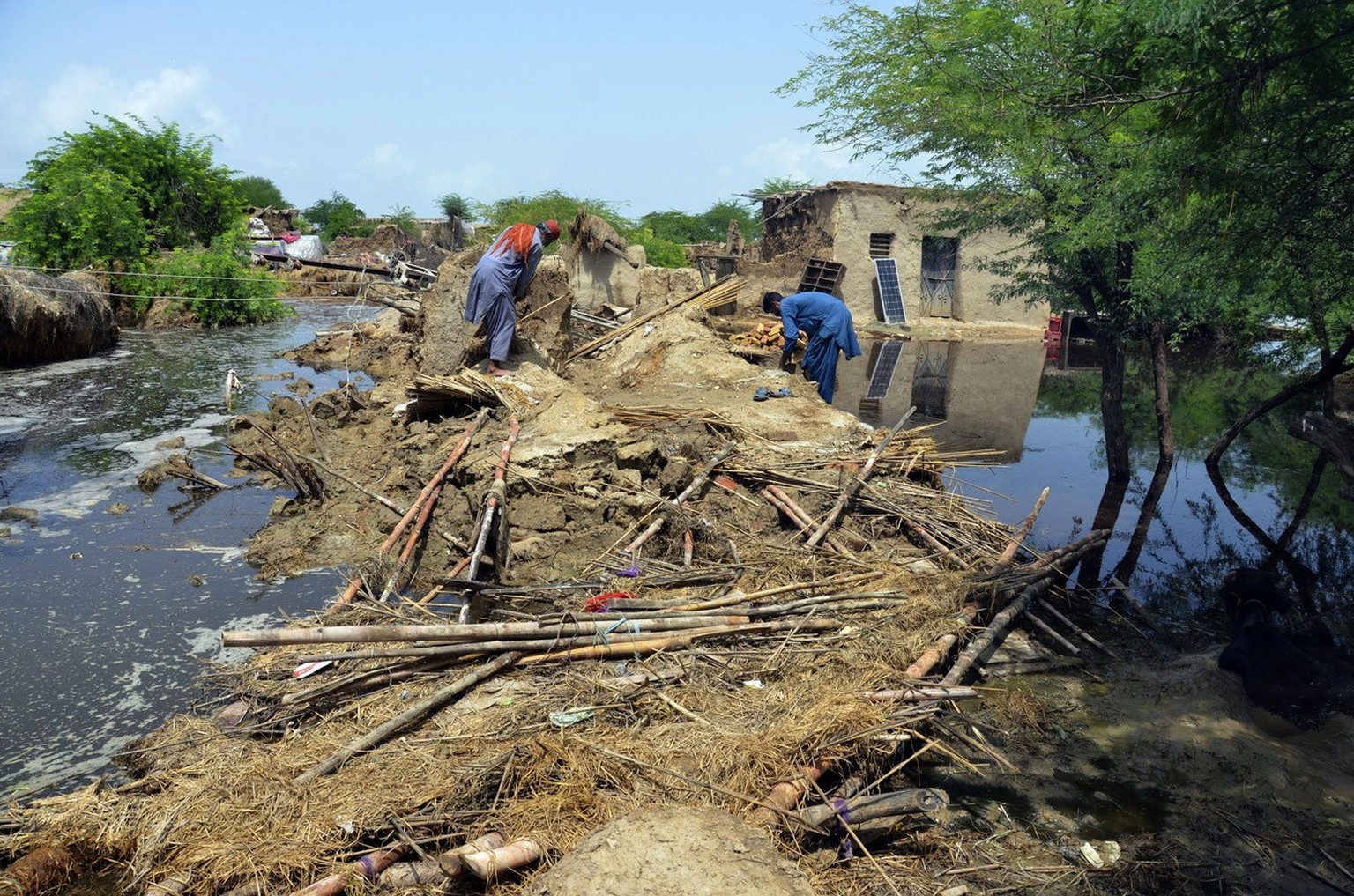 Pakistani men look for salvageable belongings from their flood-hit home surrounded by water, in Jaffarabad, a district of Pakistan&#039;s southwestern Baluchistan province, Sunday, Aug. 28, 2022. Army ...