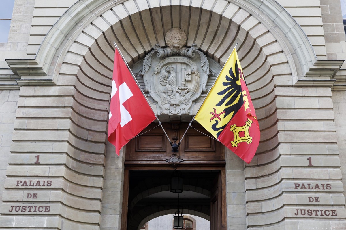 Un drapeau suisse et un drapeau genevois sont deployes au dessus de la porte d'entree du palais de justice situe dans la vieille ville, ce mardi 30 janvier 2024 a Geneve. (KEYSTONE/Salvatore Di N ...