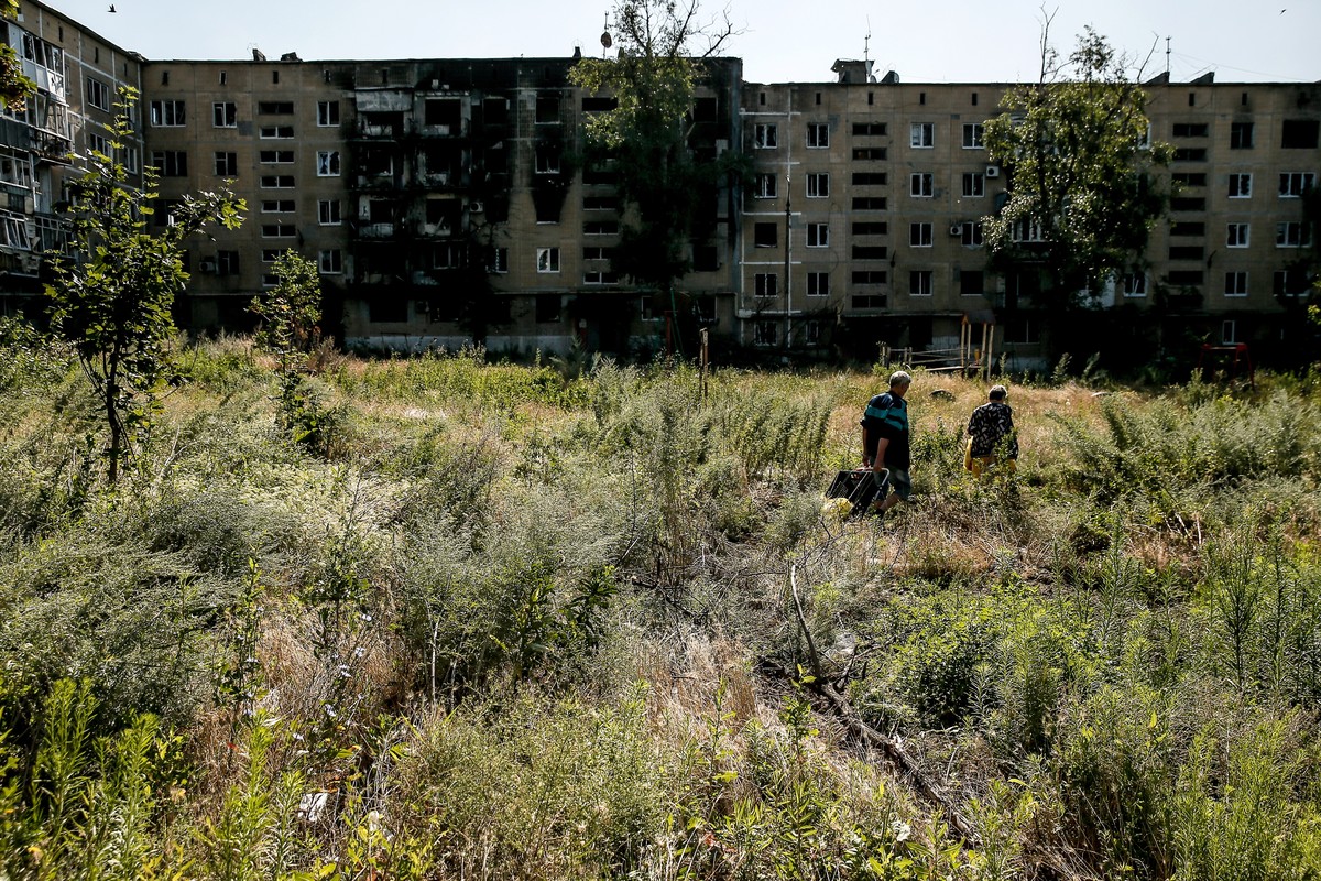 epa10750416 Local residents carry food and water in Vuhledar town, Donetsk region, Ukraine, 16 July 2023. Located in the southern part of Donetsk region, Vuhledar is a frontline town. Before Russia  ...