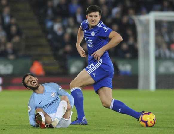 Manchester City&#039;s Bernardo Silva, left, lies on the ground after falling as Leicester&#039;s Harry Maguire follows the ball during the English Premier League soccer match between Leicester City a ...