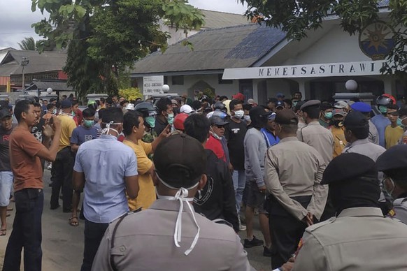 Indonesian police officers block residents during a protest on Natuna Islands, Indonesia, Sunday, Feb. 2, 2020. Several hundreds of angered residents on the islands are protesting near a quarantine facility ahead of the arrival of more than 200 evacuees from Wuhan, China. (AP Photo/Adewina)