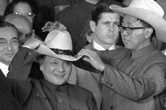 FILE - In this Feb. 2, 1979, file photo, an aide helps Chinese leader Deng Xiaoping try on a cowboy hat presented to him at a rodeo in Simonton, Texas. Four decades after the U.S. established diplomat ...