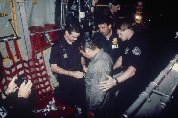 FILE - In this Jan. 4, 1990 file photo, Manuel Noriega watches as U.S. Drug Enforcement Agents place chains around his waist aboard a C-130 transport plane. A source close to the family of former Pana ...