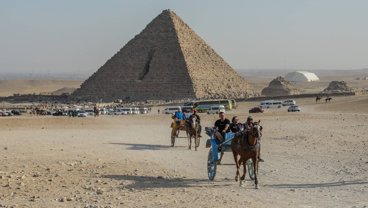 Pyramids of Giza, a popular destination for tourists in Egypt GIZA, EGYPT - FEBRUARY 14: A general view of the pyramid area where visitors travel by camels near the Great Pyramid of Giza also known as ...