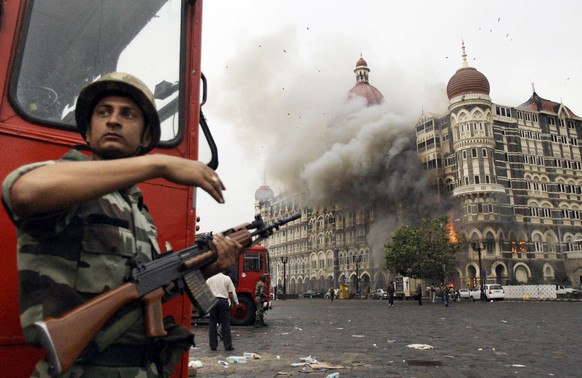 FILE- In this Nov. 29, 2008, file photo, an Indian soldier takes cover as the Taj Mahal hotel burns during gun battle between Indian military and militants inside the hotel in Mumbai, India. A Pakista ...
