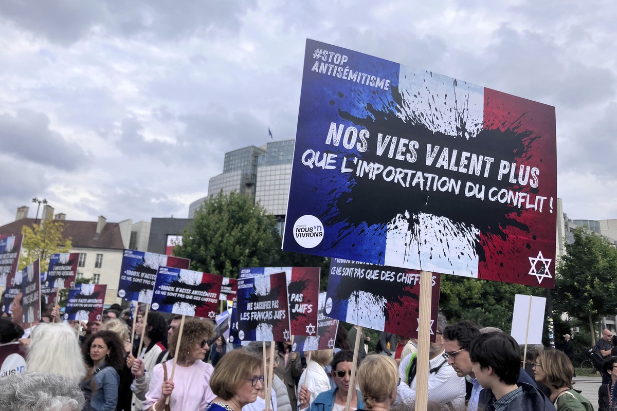 People gather against anti semitism, one carrying a placard reading "our lives worth more that an imported conflict" Thursday, June 20, 2024 in Paris. The alleged rape of a 12-year-old Jewis ...