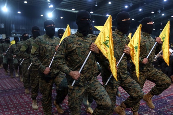 epa12390300 Hezbollah members parade carrying the group's flags during a ceremony marking the first anniversary of the killing of senior Hezbollah commander Ibrahim Aqil, in the Dahieh suburb of  ...