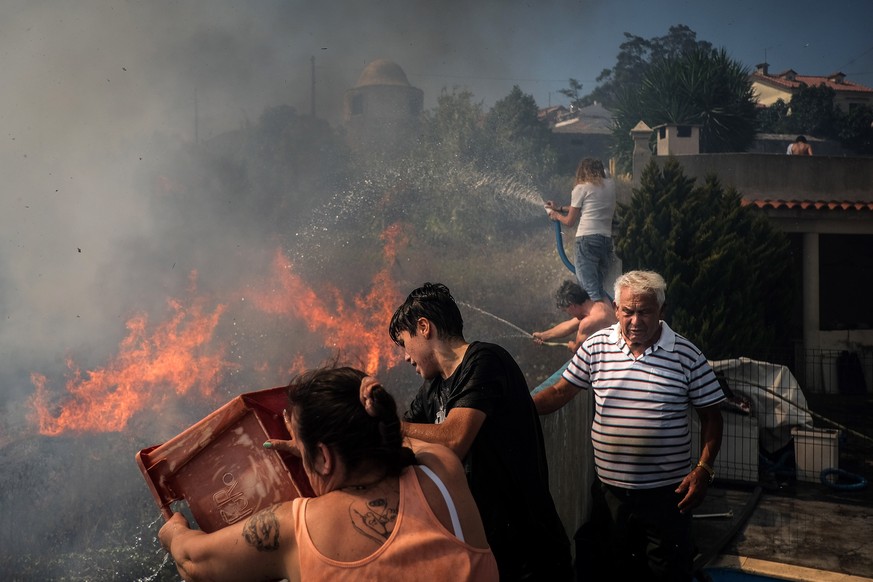 epa10064084 Inhabitants pour water onto the flames during a forest fire in Canecas, outskirts of Lisbon, Portugal, 10 July 2022. Portugal&#039;s President warned that the risk of fires will reach a pe ...