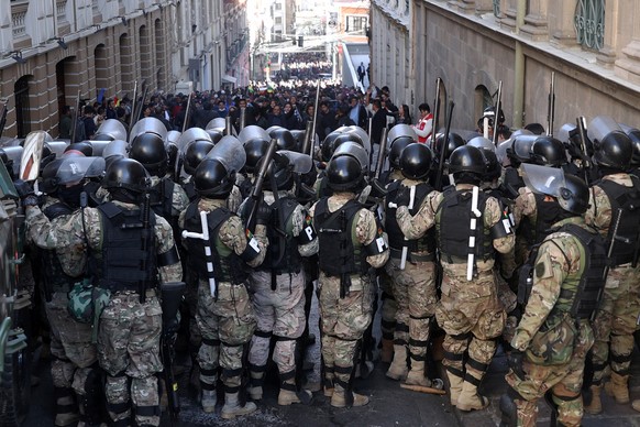 epaselect epa11440767 Military police line up in front of supporters of Bolivian President Luis Arce during a protest against military personnel trying to enter the government headquarters in La Paz,  ...
