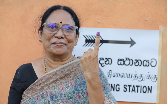 epa11719656 A Sri Lankan woman displays her ink-marked finger after voting during parliamentary elections, in Colombo, Sri Lanka, 14 November 2024. Nearly 17.1 million registered voters in Sri Lanka g ...