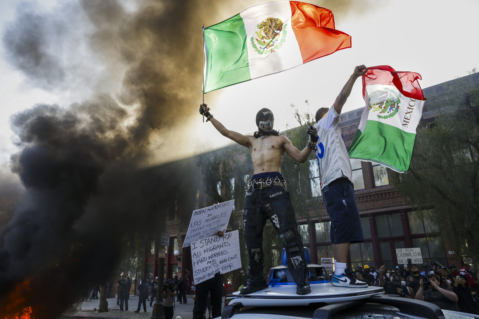 epaselect epa12165673 Activists hold aloft Mexican flags as cars burn during protests sparked by immigration raids in Los Angeles, California, USA, 08 June 2025. US President Donald Trump has deployed ...