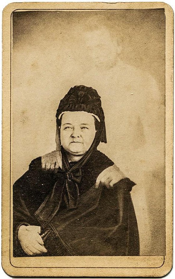 Das berühmteste Gesisterfoto von William H. Mumler: Die trauernde Mary Todd Lincoln in Witwenkleidung mit dem Geist ihres Ehemannes, dem verblichenen 16. Präsidenten der Vereinigten Staaten.