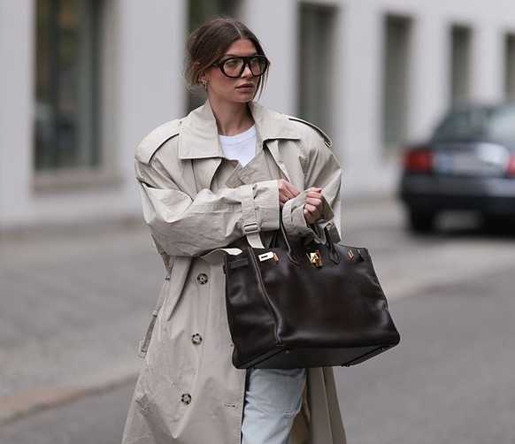 BERLIN, GERMANY - MAY 08: Sophia Geiss seen wearing an oversized cream H&amp;M x Stella McCartney trench coat paired with layered Drykorn shorts and Zara jeans, a brown Hermès Birkin 40 in Epsom leath ...