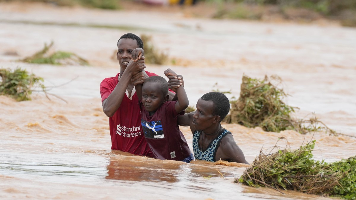 Residents help a young child while trying to cross a road damaged by El Ni