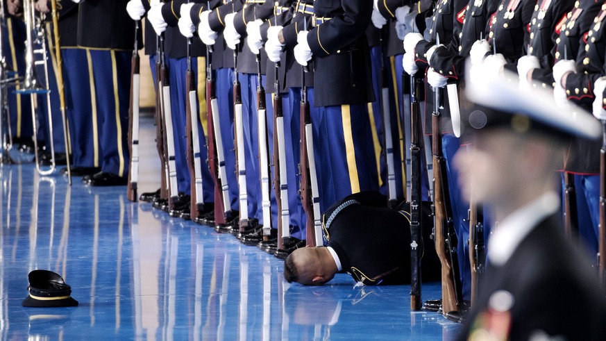 epa05698620 A member of the US Army honor guard lies on the floor after passing out during an Armed Forces Full Honor Review Farewell Tribute to US President Barack Obama at Conmy Hall, Joint Base Mye ...