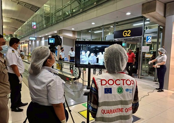 epa12680327 A handout photo released by Suvarnabhumi Airport shows Thai health officials wearing protective masks monitoring passengers from international flights arriving at Suvarnabhumi Airport, Sam ...