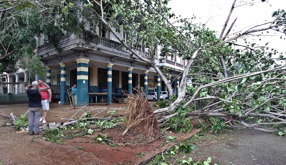 epa06196608 A group of people observe a fallen tree on a street in Havana, Cuba, 10 September 2017. Severe storm surge flooding cut power and forced the evacuation of thousands of people in the afterm ...