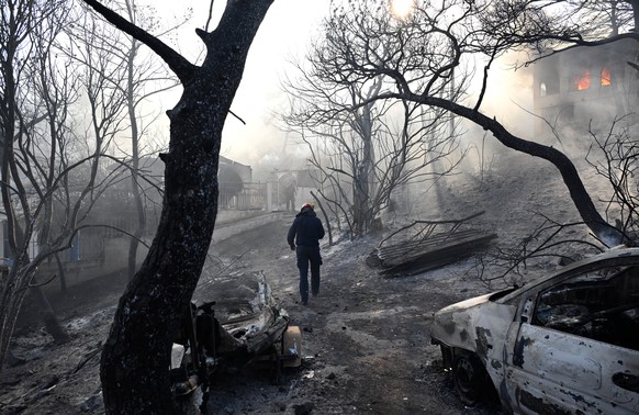 A firefighter walks through a burned area as flames engulf a house during a wildfire on the island of Salamina, west of Athens, Greece, Sunday, Aug. 16, 2026. (AP Photo/Michael Varaklas)
APTOPIX Greec ...