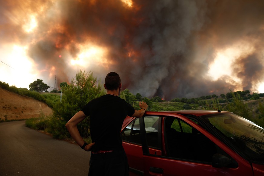 epaselect epa09398561 A man watch a wildfire in the area of Drossopigi, Varybobi, northeastern suburb of Athens, Greece, 05 August 2021. More firefighters and support by air have been added to the for ...