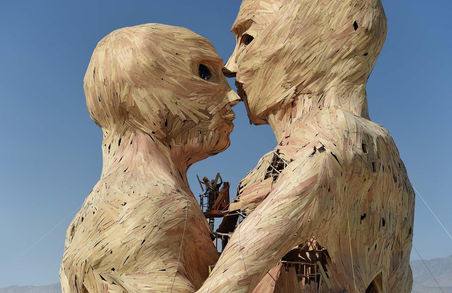 Artists and volunteers work on the art piece Embrace as they get ready for the annual Burning Man event on the Black Rock Desert in Gerlach, Nev. on Aug. 24, 2014, a day before the event opens to tick ...