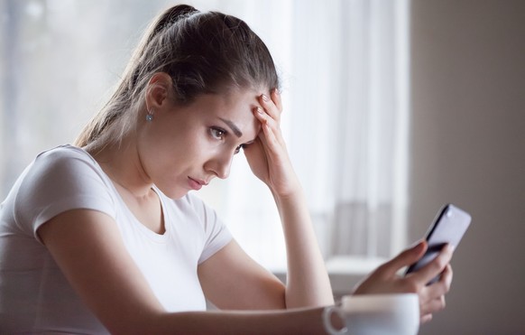 Angry young woman looking at smartphone frustrated by no signal or scam message, mad female disappointed by bad news reading on phone, upset girl get negative or rejection response on mobile
