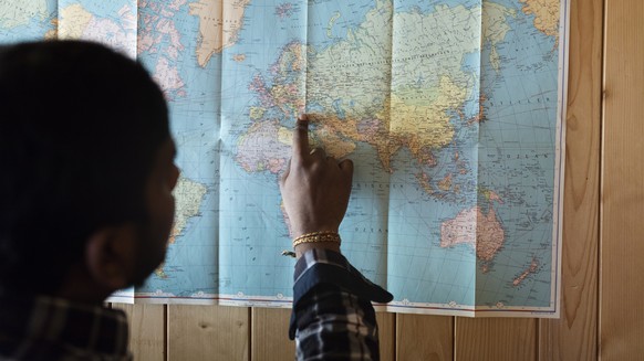 Ein Asylsuchender zeigt auf einer Karte seinen Fluchtweg.