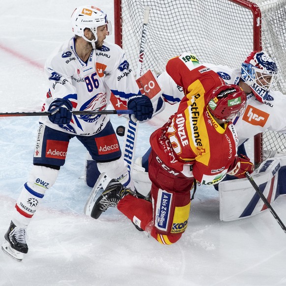 Biels Mike Kuenzle, Mitte, im Duell mit Zuerichs Dario Trutmann, links, und Torhueter Lukas Flueeler im Eishockey Meisterschaftsspiel der National League zwischen dem EHC Biel und den ZSC Lions, am Di ...